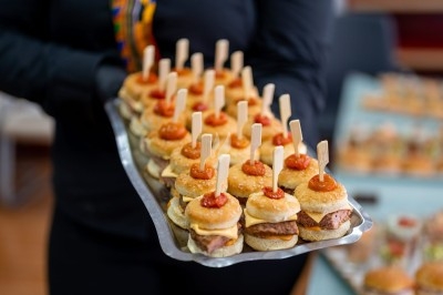 Assortiment de wraps garnis de légumes et de poulet, entourés de petits pains et de sandwichs sur un plateau.