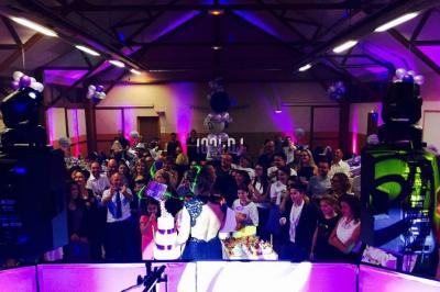 Un couple de mariés danse au milieu d'effets de fumée et d'étincelles dans une salle de réception décorée.