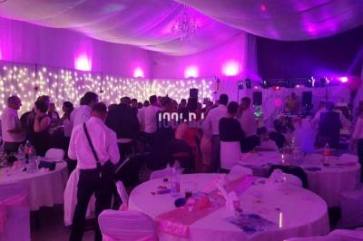 Un couple de mariés danse au milieu d'effets de fumée et d'étincelles dans une salle de réception décorée.