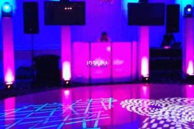 Un couple de mariés danse au milieu d'effets de fumée et d'étincelles dans une salle de réception décorée.