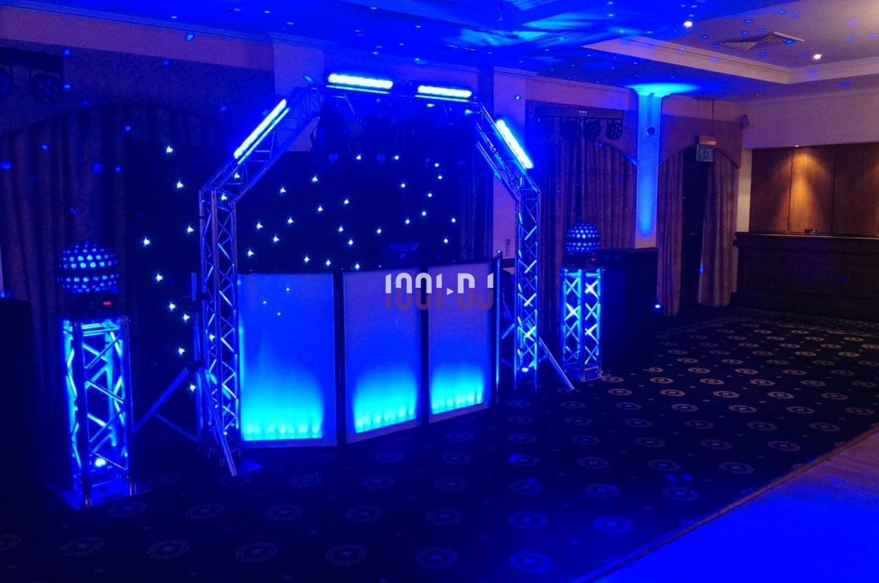 Installation lumineuse bleue avec une arche métallique, des spots et un fond étoilé dans une salle sombre.