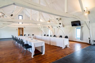 Salle lumineuse avec bar en bois, tables en verre, chaises noires et grandes fenêtres laissant entrer la lumière naturelle.