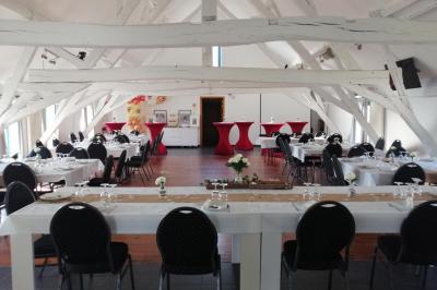 Salle lumineuse avec bar en bois, tables en verre, chaises noires et grandes fenêtres laissant entrer la lumière naturelle.