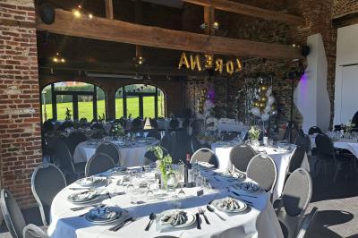 Salle lumineuse avec bar en bois, tables en verre, chaises noires et grandes fenêtres laissant entrer la lumière naturelle.