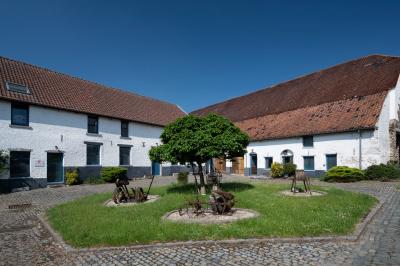 Salle en briques avec poutres apparentes, tables hautes noires et grandes ouvertures donnant sur un espace extérieur.
