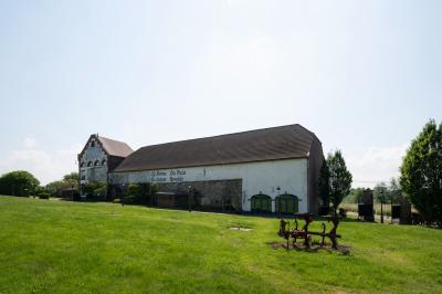 Salle en briques avec poutres apparentes, tables hautes noires et grandes ouvertures donnant sur un espace extérieur.