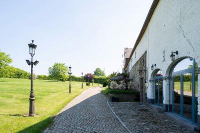 Salle en briques avec poutres apparentes, tables hautes noires et grandes ouvertures donnant sur un espace extérieur.