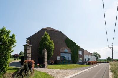 Salle en briques avec poutres apparentes, tables hautes noires et grandes ouvertures donnant sur un espace extérieur.