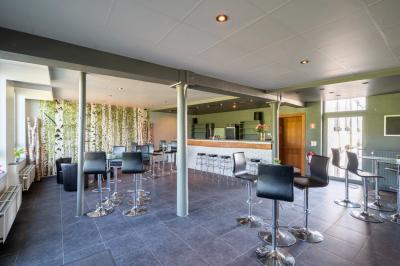 Salle en briques avec poutres apparentes, tables hautes noires et grandes ouvertures donnant sur un espace extérieur.