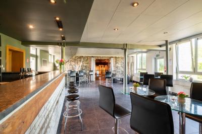 Salle en briques avec poutres apparentes, tables hautes noires et grandes ouvertures donnant sur un espace extérieur.