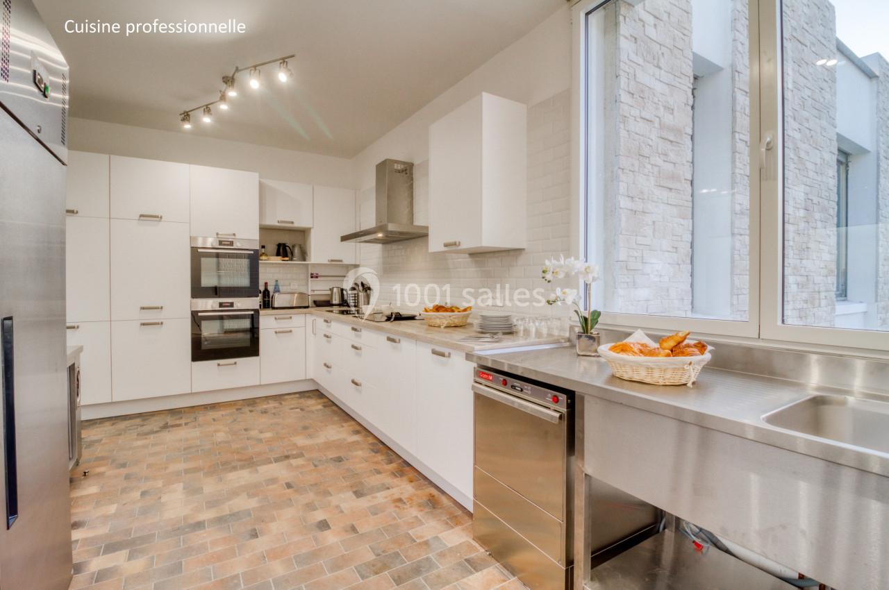 Cuisine moderne avec équipements professionnels, plan de travail en inox, four encastré et sol en carrelage.