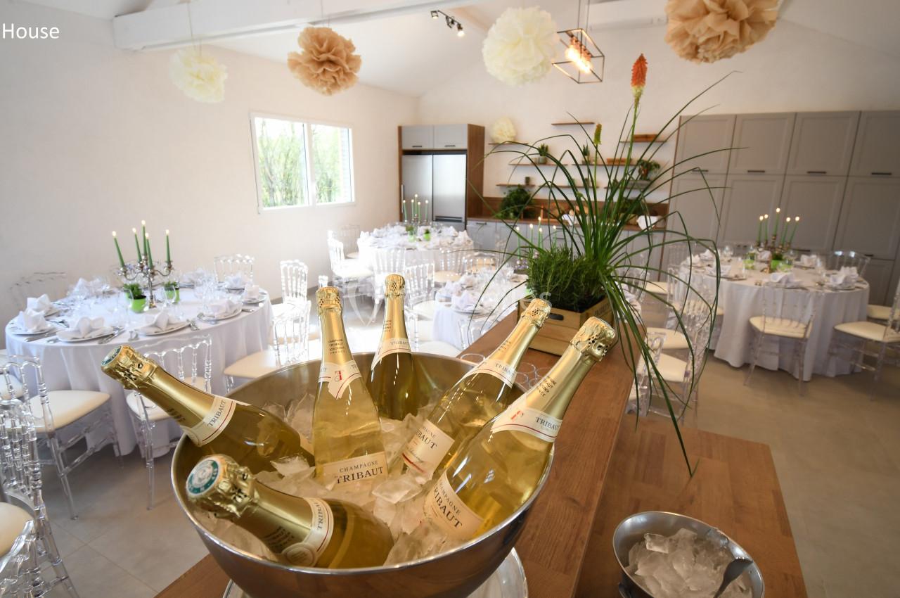Salle de réception lumineuse décorée avec des tables dressées et un seau rempli de bouteilles de vin pétillant.
