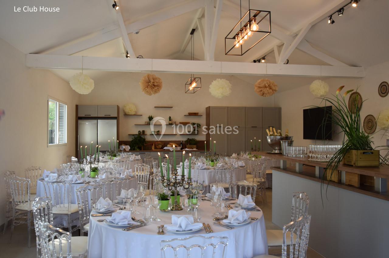Salle de réception décorée avec des tables rondes dressées, des chandeliers et des éléments suspendus en papier.