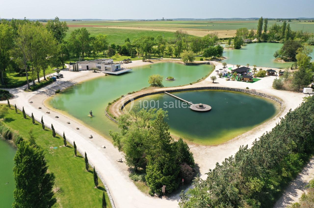 Vue aérienne d'un parc avec plusieurs étangs, espaces verts, chemins et bâtiments entourés de végétation.