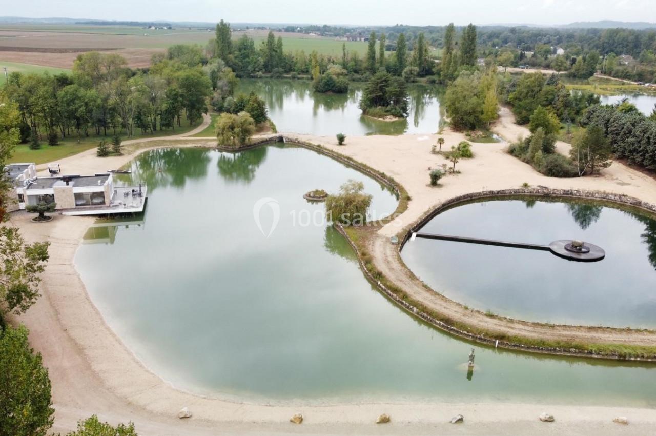 Vue aérienne d'un parc avec plusieurs étangs, plages de sable et végétation environnante dans un paysage rural.