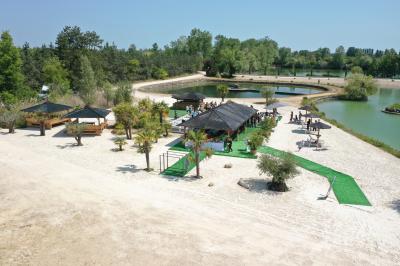 Vue aérienne d'un parc avec plusieurs étangs, espaces verts, chemins et bâtiments entourés de végétation.
