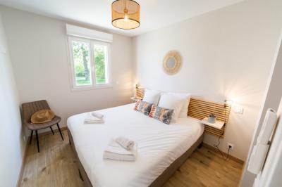 Vue aérienne d'un parc avec plusieurs étangs, espaces verts, chemins et bâtiments entourés de végétation.