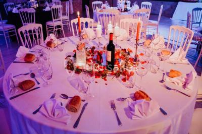 Salle vide avec un sol en parquet sombre, murs blancs, fenêtres et piliers gris sous un plafond à dalles blanches.