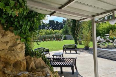 Salle vide avec un sol en parquet sombre, murs blancs, fenêtres et piliers gris sous un plafond à dalles blanches.