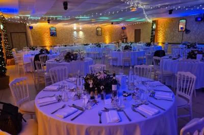Salle vide avec un sol en parquet sombre, murs blancs, fenêtres et piliers gris sous un plafond à dalles blanches.