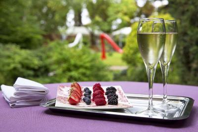 Deux chaises en bois et une table ronde avec un seau à glace sur une terrasse donnant sur un jardin verdoyant.
