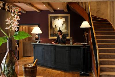 Deux chaises en bois et une table ronde avec un seau à glace sur une terrasse donnant sur un jardin verdoyant.