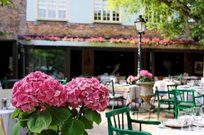 Deux chaises en bois et une table ronde avec un seau à glace sur une terrasse donnant sur un jardin verdoyant.