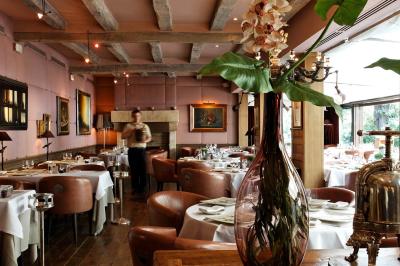 Deux chaises en bois et une table ronde avec un seau à glace sur une terrasse donnant sur un jardin verdoyant.