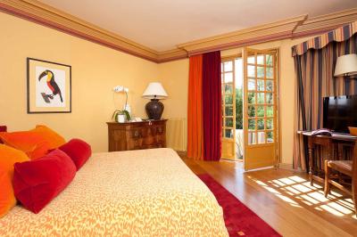 Deux chaises en bois et une table ronde avec un seau à glace sur une terrasse donnant sur un jardin verdoyant.