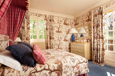 Deux chaises en bois et une table ronde avec un seau à glace sur une terrasse donnant sur un jardin verdoyant.