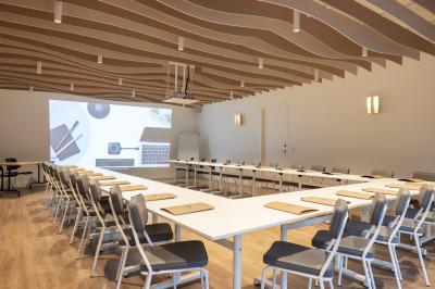 Salle de restaurant moderne avec tables en bois dressées, chaises rembourrées et lumière naturelle.