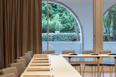 Salle de restaurant moderne avec tables en bois dressées, chaises rembourrées et lumière naturelle.