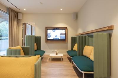 Salle de restaurant moderne avec tables en bois dressées, chaises rembourrées et lumière naturelle.