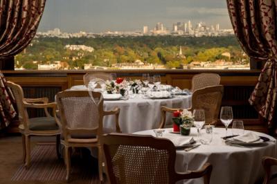 Façade d'un bâtiment blanc avec une enseigne ’Pavillon Henri IV Restaurant’, entouré de verdure et d'une clôture.
