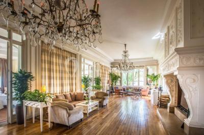 Façade d'un bâtiment blanc avec une enseigne ’Pavillon Henri IV Restaurant’, entouré de verdure et d'une clôture.