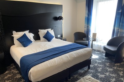 Salle de bain moderne avec douche à l'italienne, carrelage à motifs noirs et blancs, lavabo et miroir éclairé.