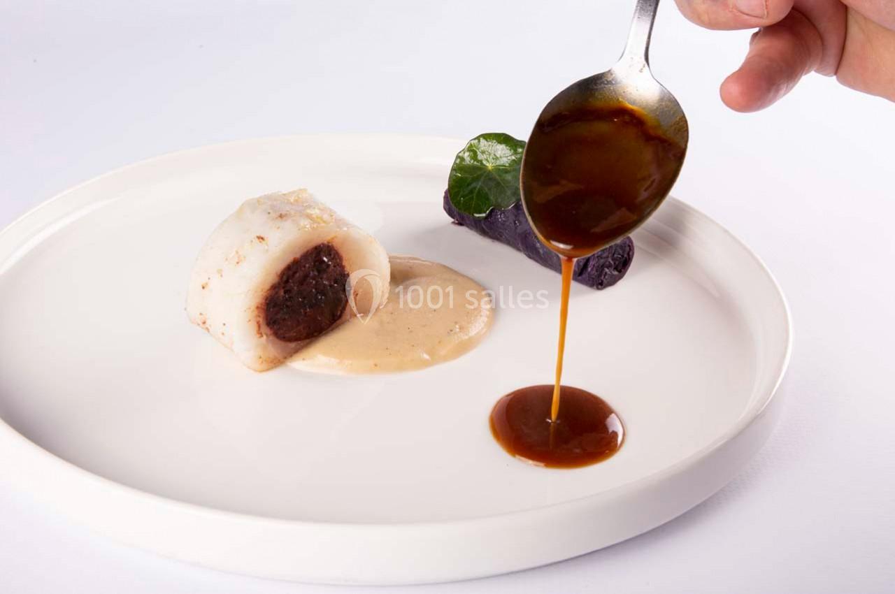 Un plat gastronomique avec un rouleau de poisson farci, purée violette et sauce versée à la cuillère.