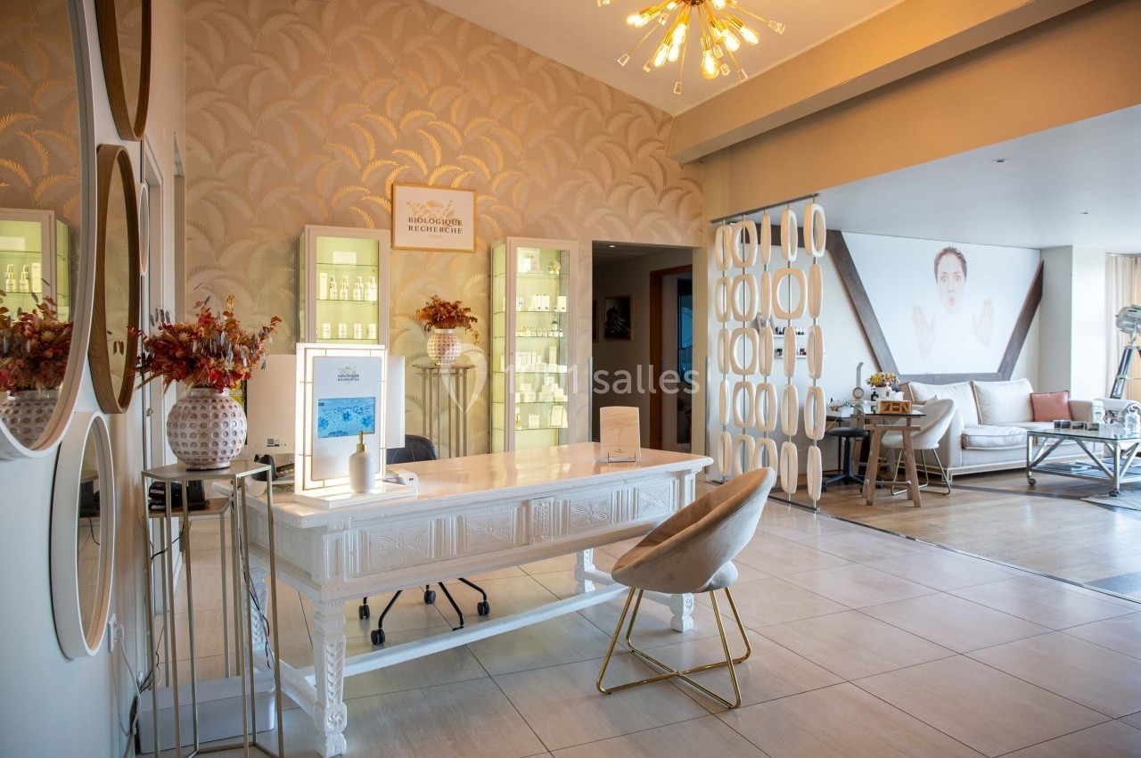 Intérieur d'un salon moderne avec un bureau blanc, des étagères éclairées, des décorations élégantes et un coin salon.