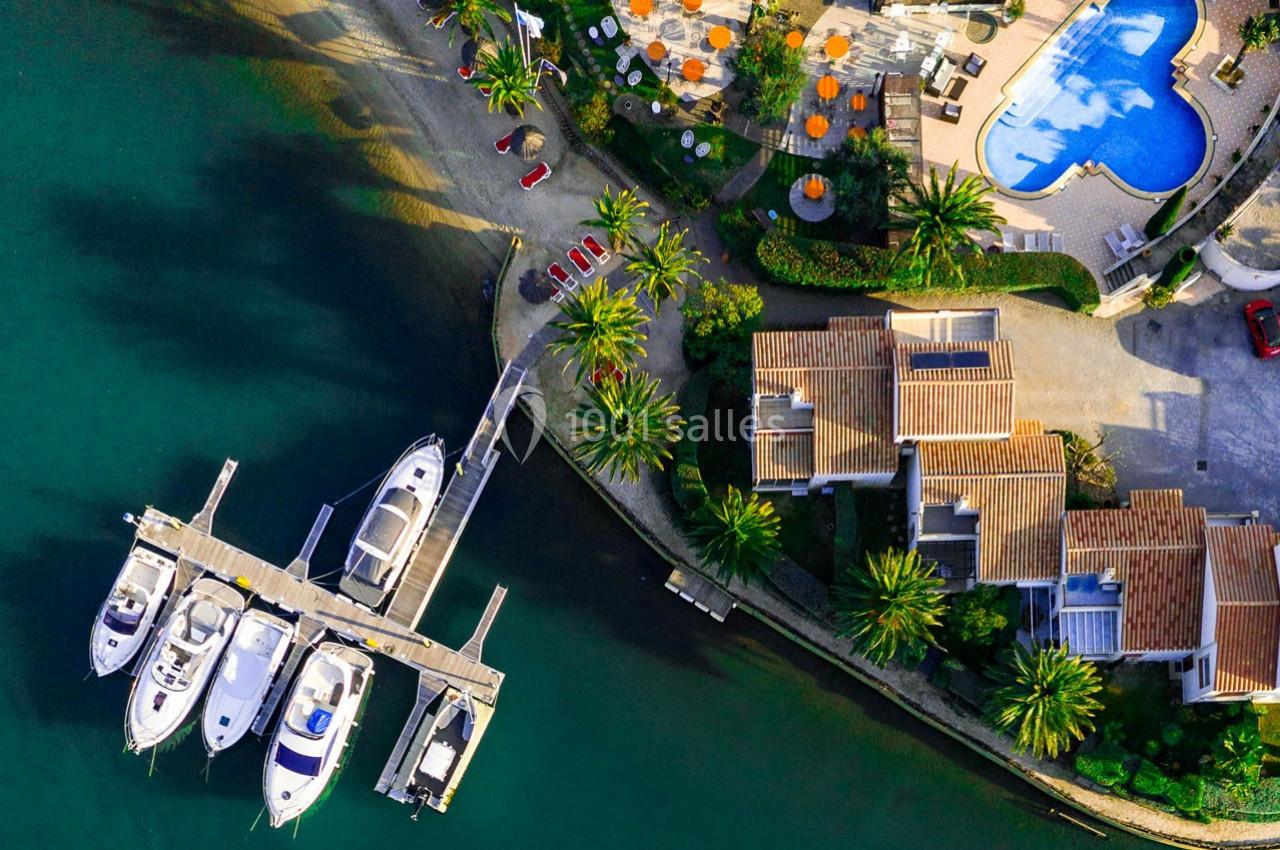 Vue aérienne d'un port avec des yachts amarrés, des maisons avec toits en tuiles et une piscine en forme de cœur.