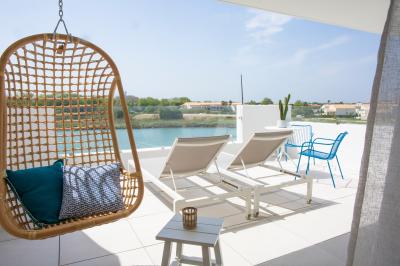 Terrasse ensoleillée avec tables et chaises bleues, décorée de plantes et d'un panneau indiquant ’La plage’.