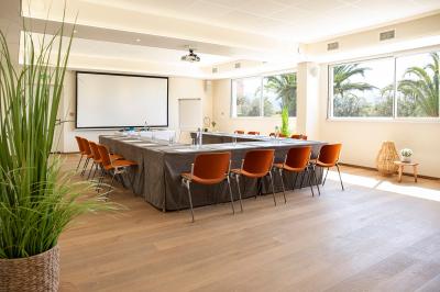 Terrasse ensoleillée avec tables et chaises bleues, décorée de plantes et d'un panneau indiquant ’La plage’.