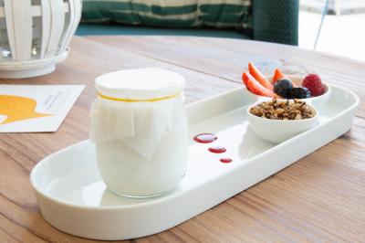 Terrasse ensoleillée avec tables et chaises bleues, décorée de plantes et d'un panneau indiquant ’La plage’.