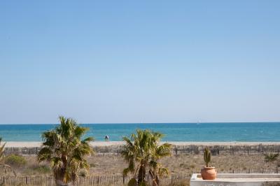 Terrasse ensoleillée avec tables et chaises bleues, décorée de plantes et d'un panneau indiquant ’La plage’.