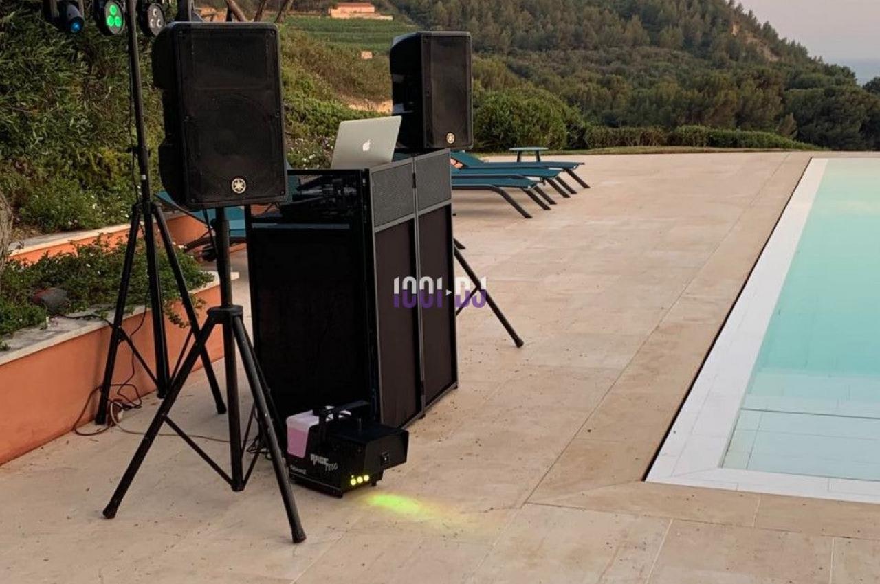 Équipement de sonorisation installé en extérieur près d'une piscine, avec vue sur des collines et un ciel dégagé.