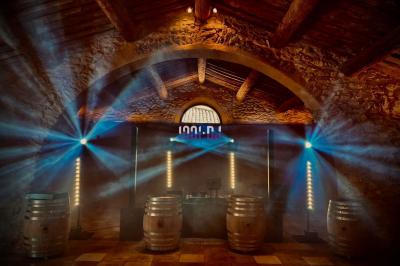 Personnes dans une ambiance tamisée, discutant et dansant près d'un bar décoré de fleurs suspendues.