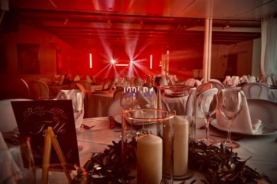 Personnes dans une ambiance tamisée, discutant et dansant près d'un bar décoré de fleurs suspendues.