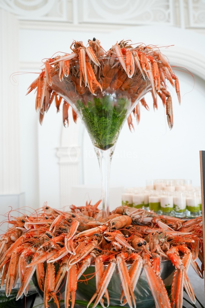 Plateau de langoustines présentées dans une grande coupe en verre, décorée de verdure.