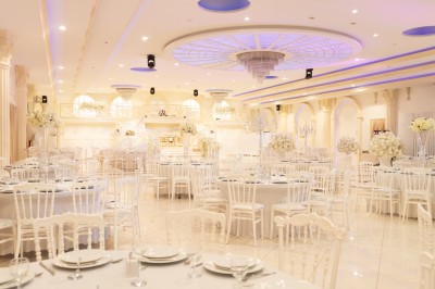 Salle de conférence lumineuse avec tables disposées en U, chaises noires et un tableau noir au fond.