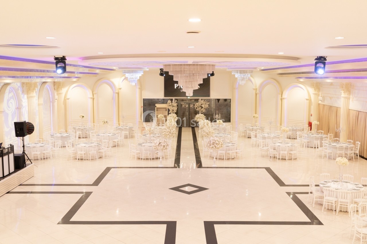 Salle de réception spacieuse avec tables rondes décorées de fleurs blanches et éclairage élégant.