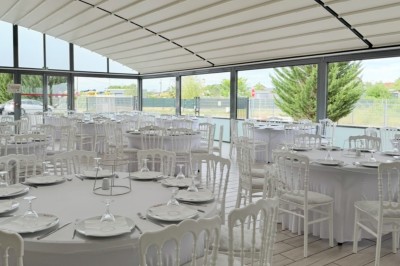 Salle de conférence lumineuse avec tables disposées en U, chaises noires et un tableau noir au fond.